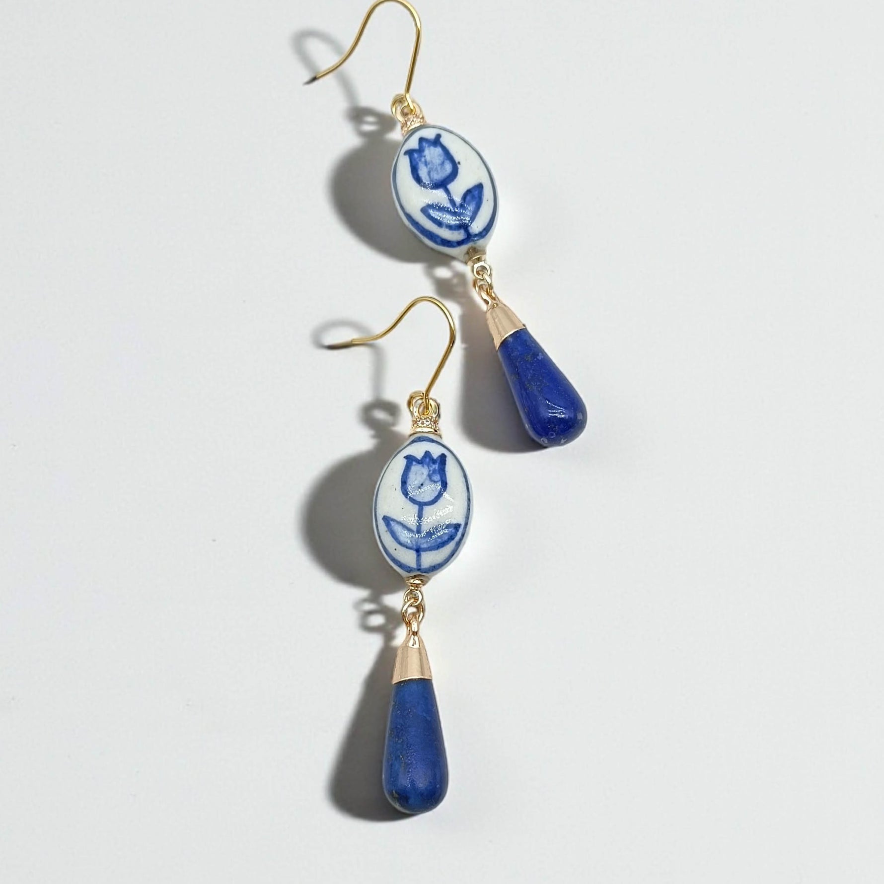 Pair of earrings with blue and white floral design on a light gray background