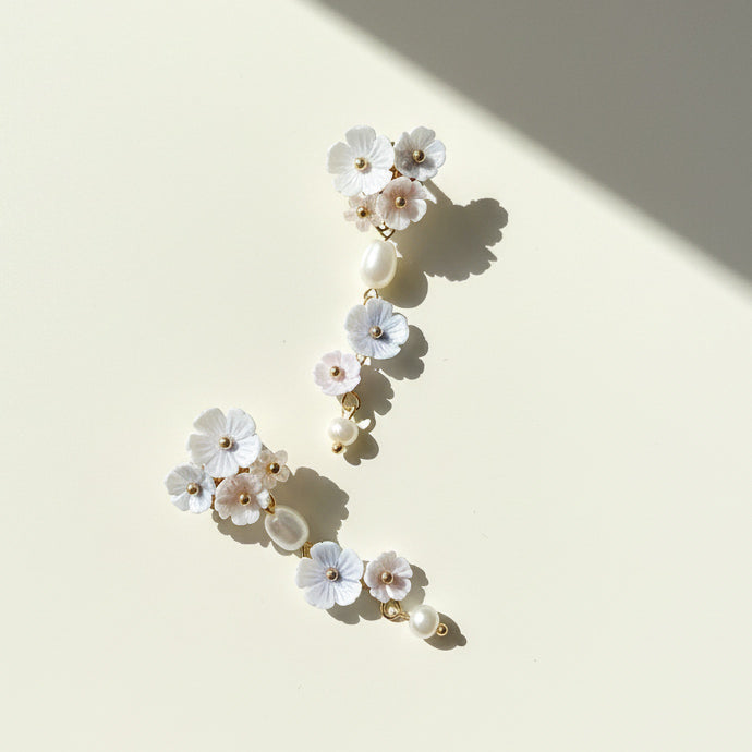 Hand-painted pastel flower earrings with freshwater pearls on cream background, sunlight and shadow.