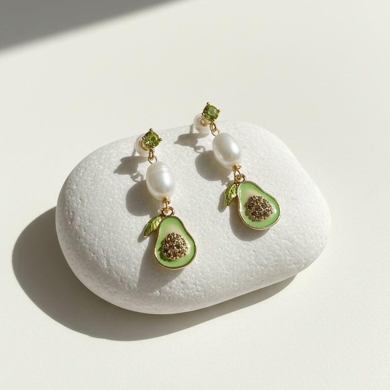 Avocado drop earrings with pearls displayed on white stone.