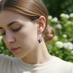 Model wearing A2K London grape and pearl drop earrings in garden sunlight, elegant and playful look.