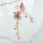 Pink floral earrings with gold accents on a marble background