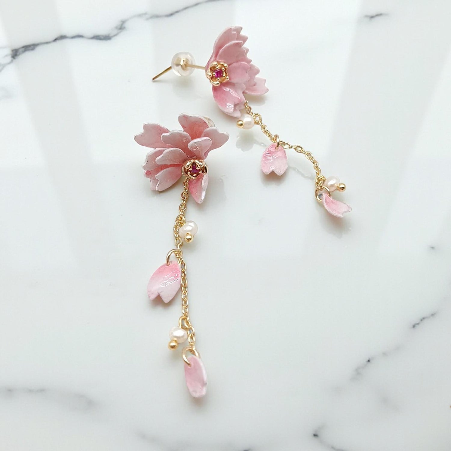 Pink floral earrings with gold accents on a marble background