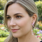 Woman wearing floral earrings with a blurred garden background