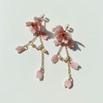 Pair of pink floral earrings with gold chains on a light background