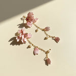 Delicate bracelet with pink floral charms on a light background