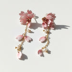 Pair of pink floral earrings with gold chains on a light background