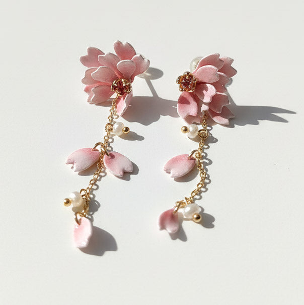 Pair of pink floral earrings with gold chains on a light background
