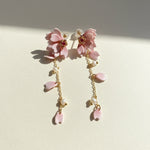 Pair of pink floral earrings with gold chains on a light background