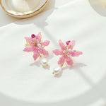 Pink floral earrings with pearls on a white surface