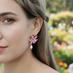 Close-up of a woman wearing pink floral earrings with a blurred garden background