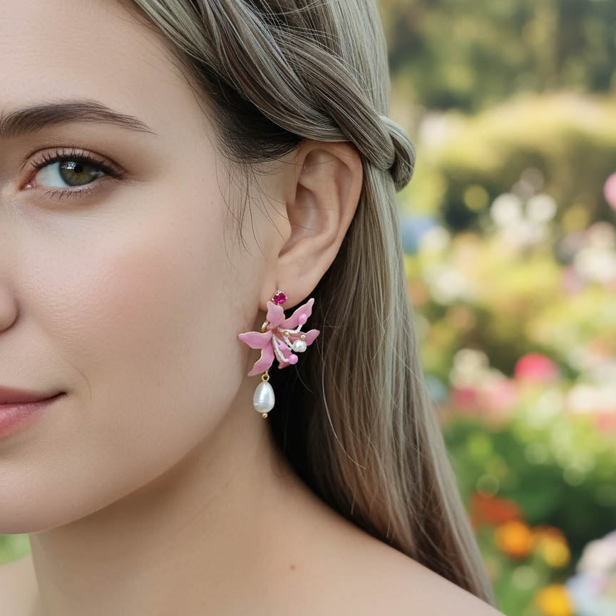 Close-up of a woman wearing pink floral earrings with a blurred garden background