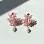Pink floral earrings with pearl drops on a white background