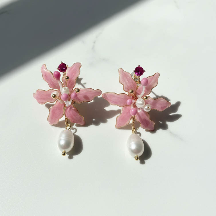 Pink floral earrings with pearl drops on a white background