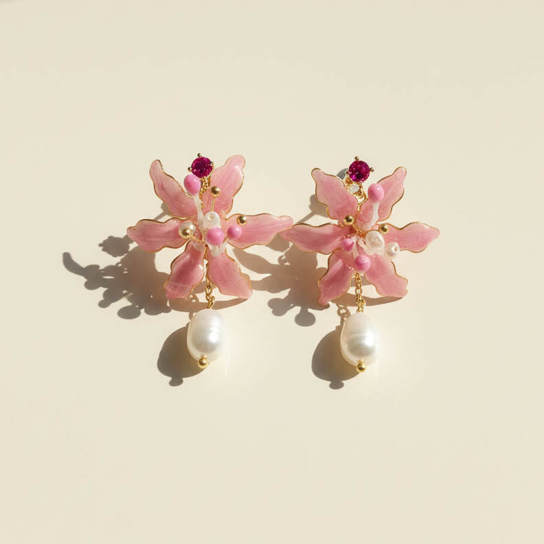 Pink spider lily flower earrings with pearl drops on a beige background