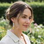 Model wearing A2K London lemon and pearl earrings in garden sunlight, Mediterranean summer style.