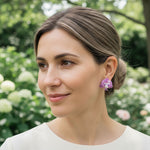 Model wearing handcrafted purple orchid clip-on earrings outdoors