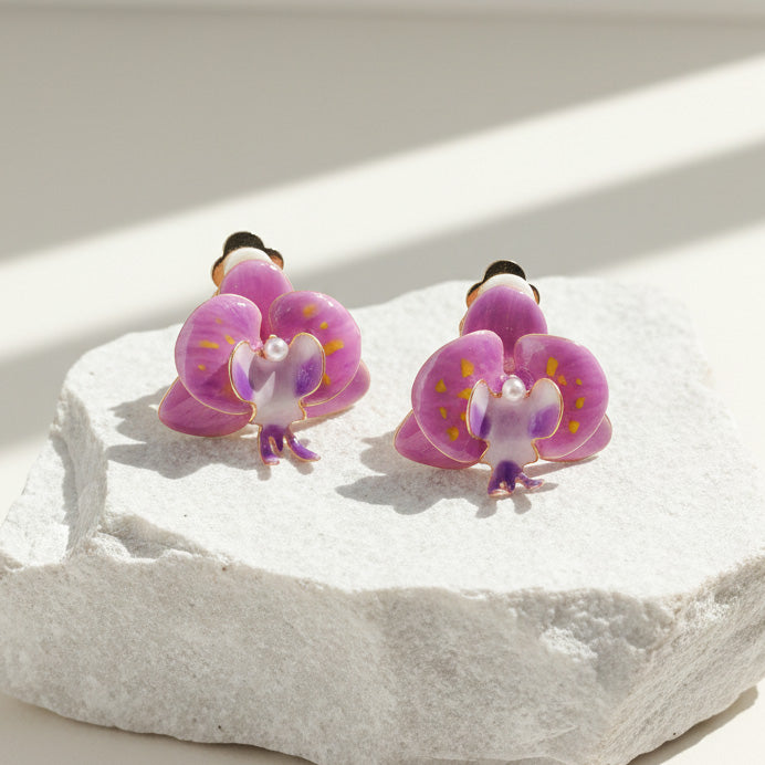 Hand-painted purple orchid resin clip-on earrings on stone display