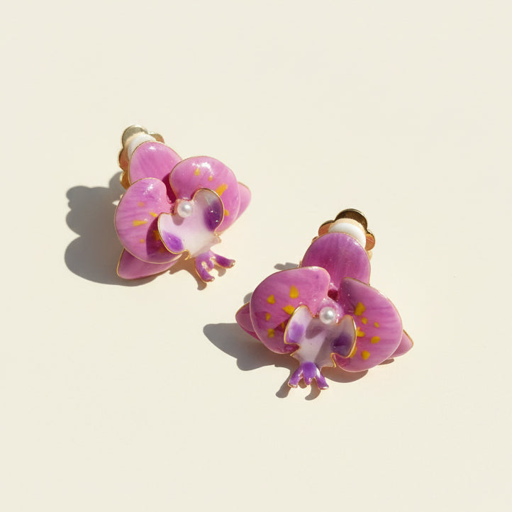Close-up of handcrafted resin orchid clip-on earrings in sunlight