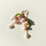 Delicate earrings with pink floral elements and gold accents on a light background