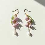 Pair of floral earrings with pink flowers and gold accents on a light background