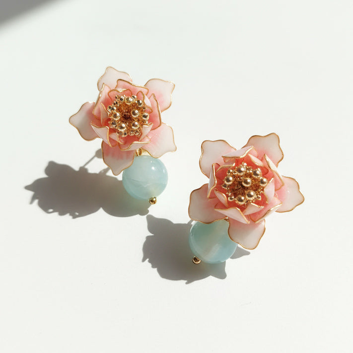 Handcrafted pink lotus and amazonite stud earrings in sunlight.