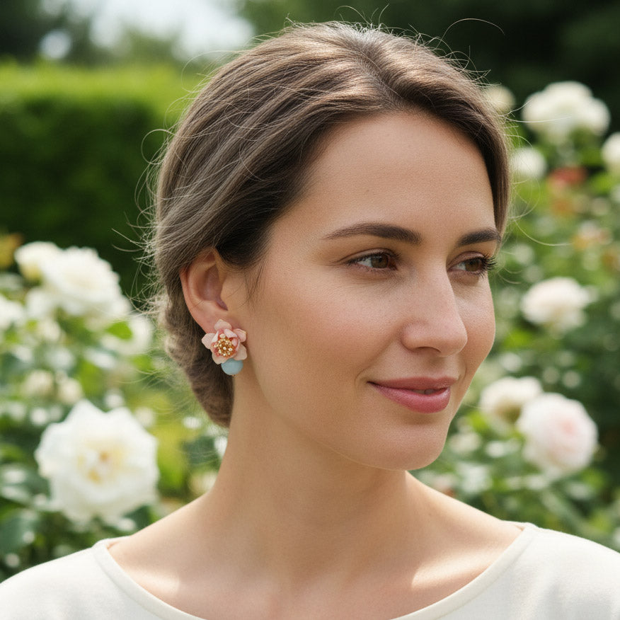 Model wearing pink lotus flower earrings with amazonite stones in garden.