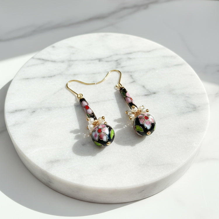 Cloisonné enamel bead earrings with freshwater pearl accents on a marble surface