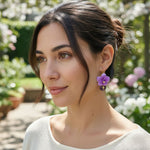 Model wearing handcrafted purple orchid and amethyst drop earrings in garden setting