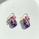Close-up of amethyst drop earrings with pink resin flowers and CZ stones.