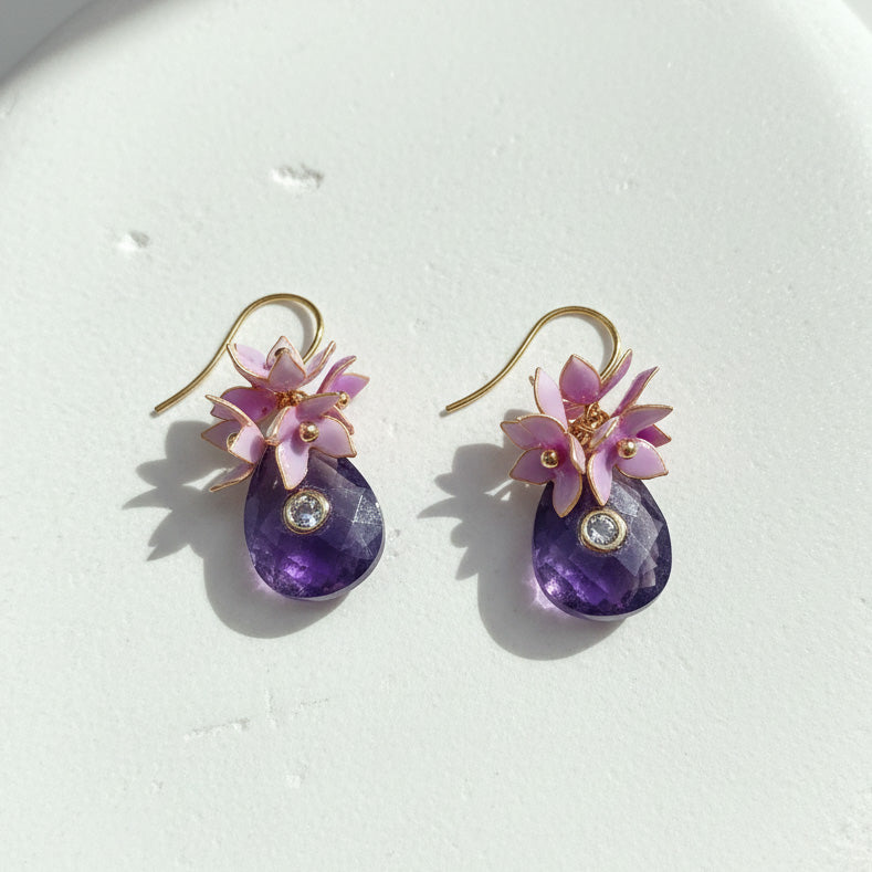 Close-up of amethyst drop earrings with pink resin flowers and CZ stones.