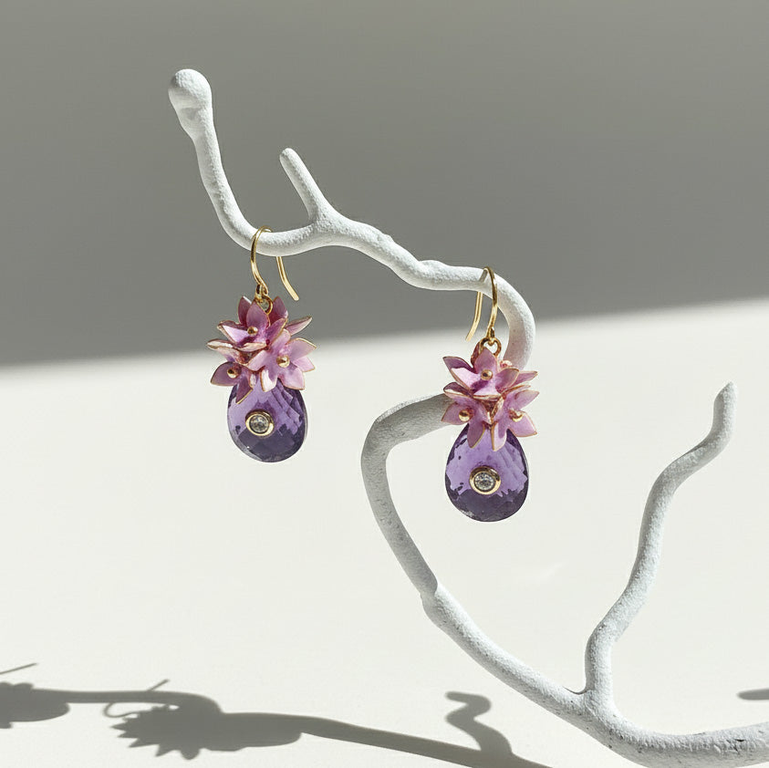 Artistic floral earrings hanging from branch in soft light.