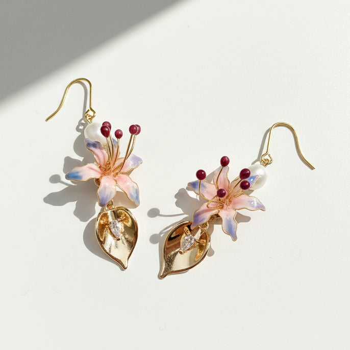 Hand-painted pink lily and gold leaf drop earrings with freshwater pearls on white background, sunlight and shadow
