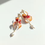 Floral enamel and pearl drop earrings with CZ accents in sunlight.
