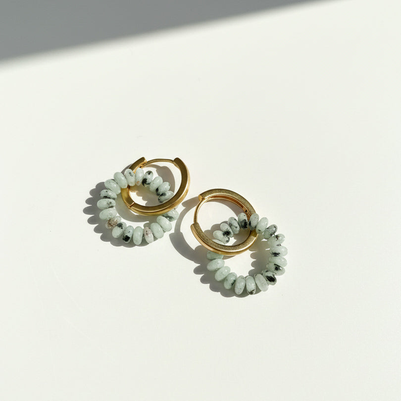 Gold hoops with jade-green beaded ring attachments.