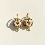 Close-up of cloisonné enamel earrings with pearl detailing in sunlight.