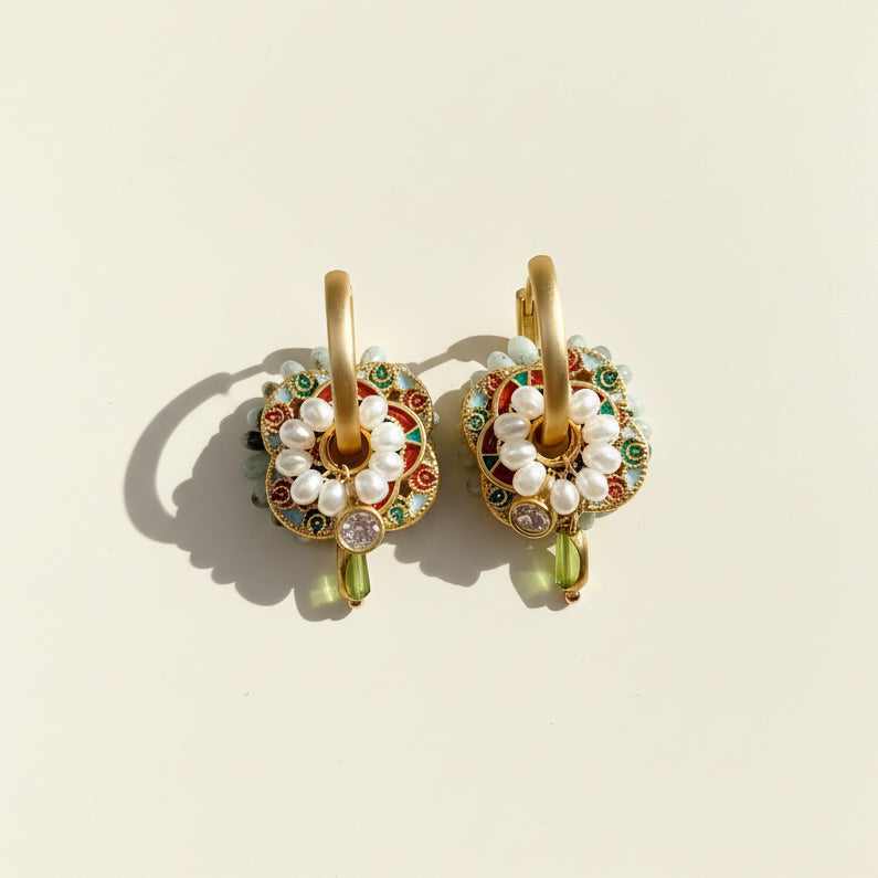 Close-up of cloisonné enamel earrings with pearl detailing in sunlight.