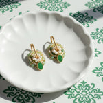 Close-up of green cloisonné floral earrings with pearls on white dish