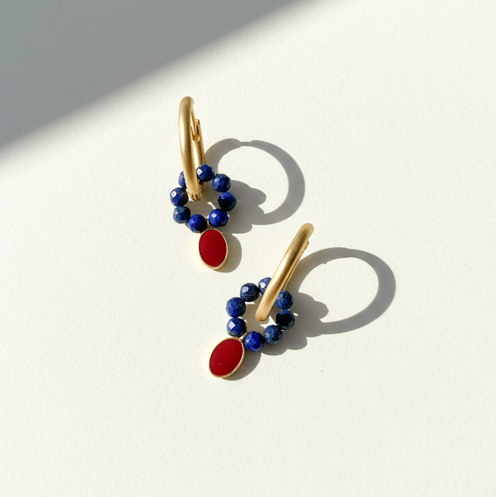 Gold earrings with blue and red stones on a white background