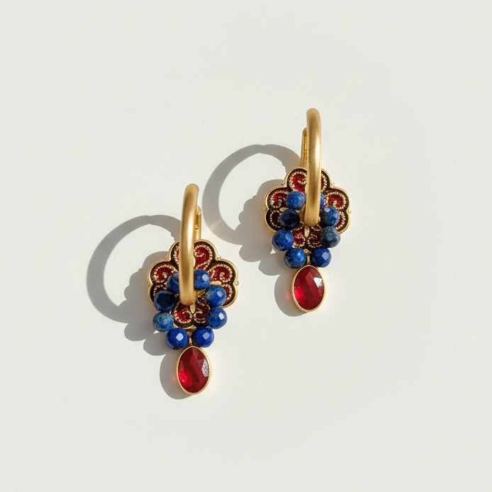 Gold earrings with blue and red stones on a light gray background