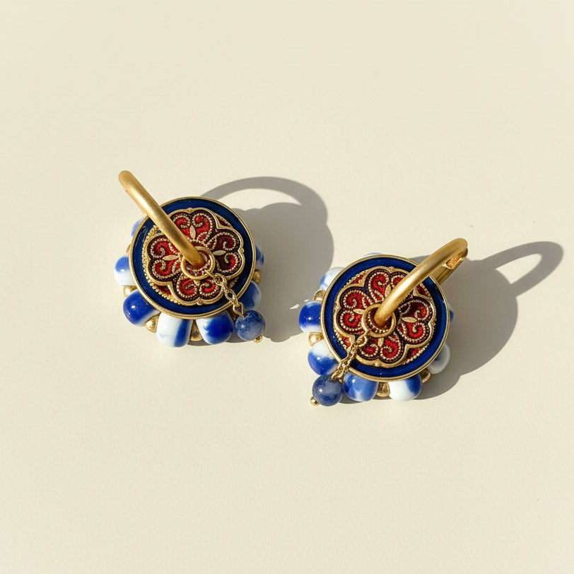 Decorative earrings with blue, red, and gold colors on a beige background
