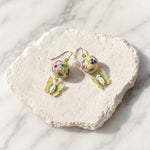 Butterfly Pearl Drop Earrings Featuring Hand-Painted Floral Porcelain Beads on a textured stone surface.