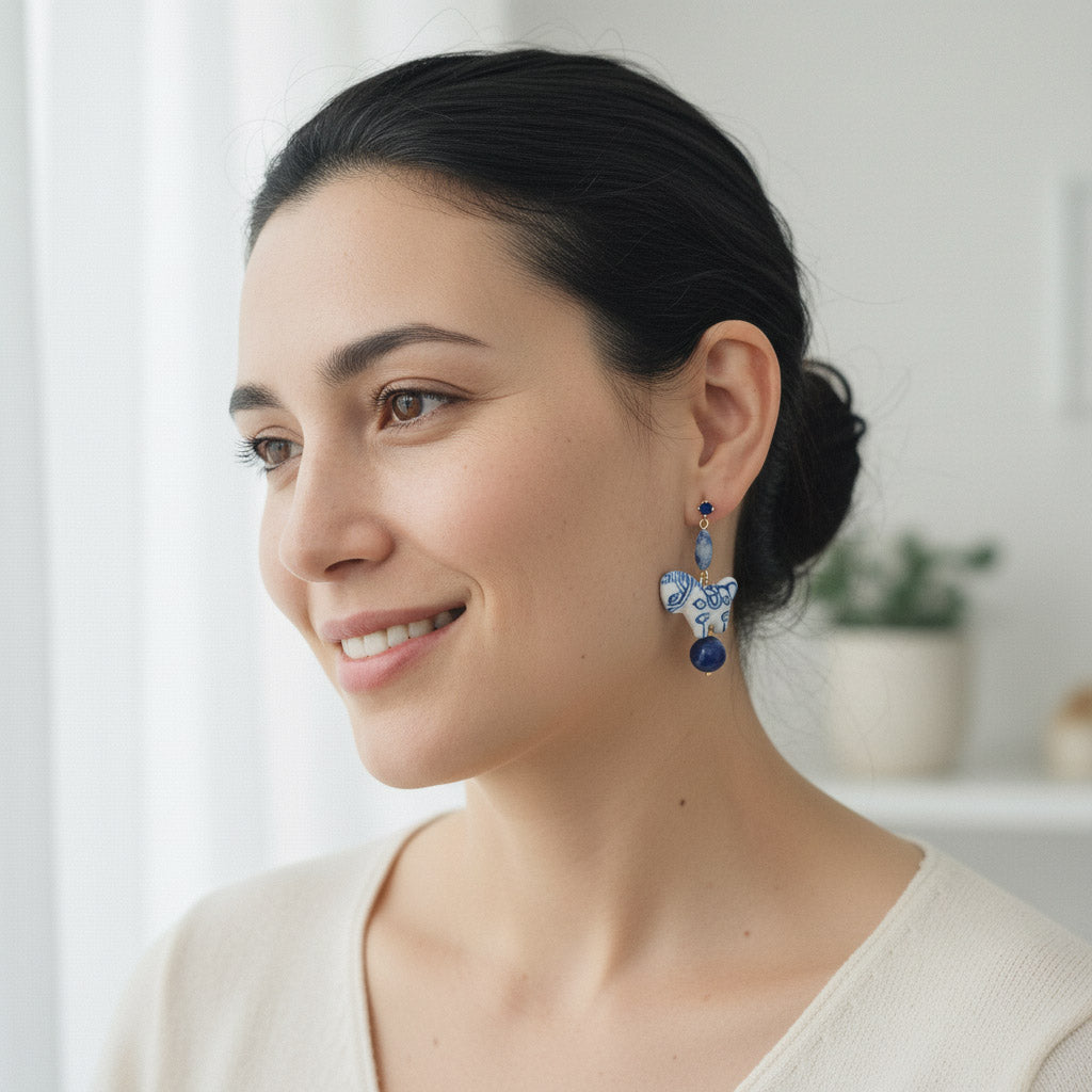 Woman wearing blue and white earrings with a neutral background