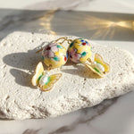 Colorful hand painted porcelain floral beads and butterfly earrings on a light stone surface