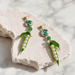 Pea Pod & Baroque Pearl Drop Earrings featuring hand-painted enamel pea pods, glass pearls, hand-painted baroque pearls, jade beads and CZ studs on a textured white stone surface.