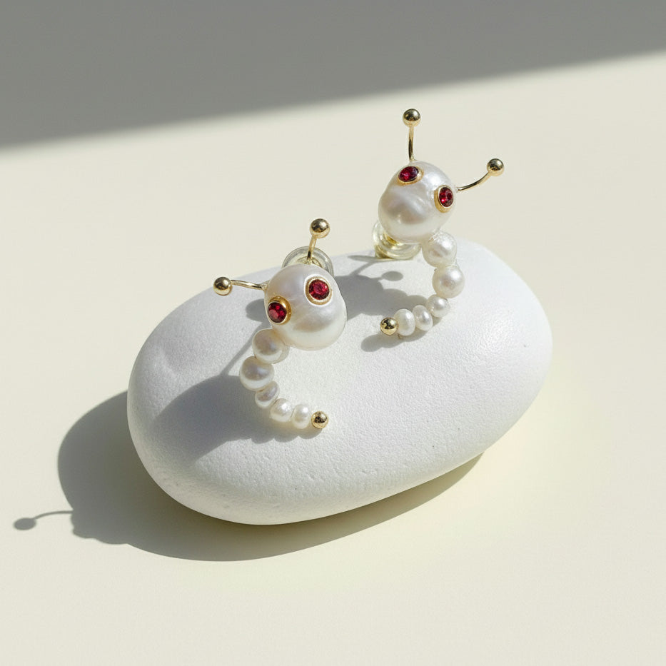 Pair of pearl earrings with red gemstones on a white stone