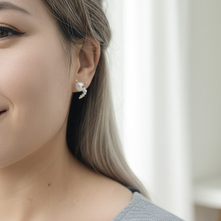 Close-up of a person wearing pearl earrings with a blurred background