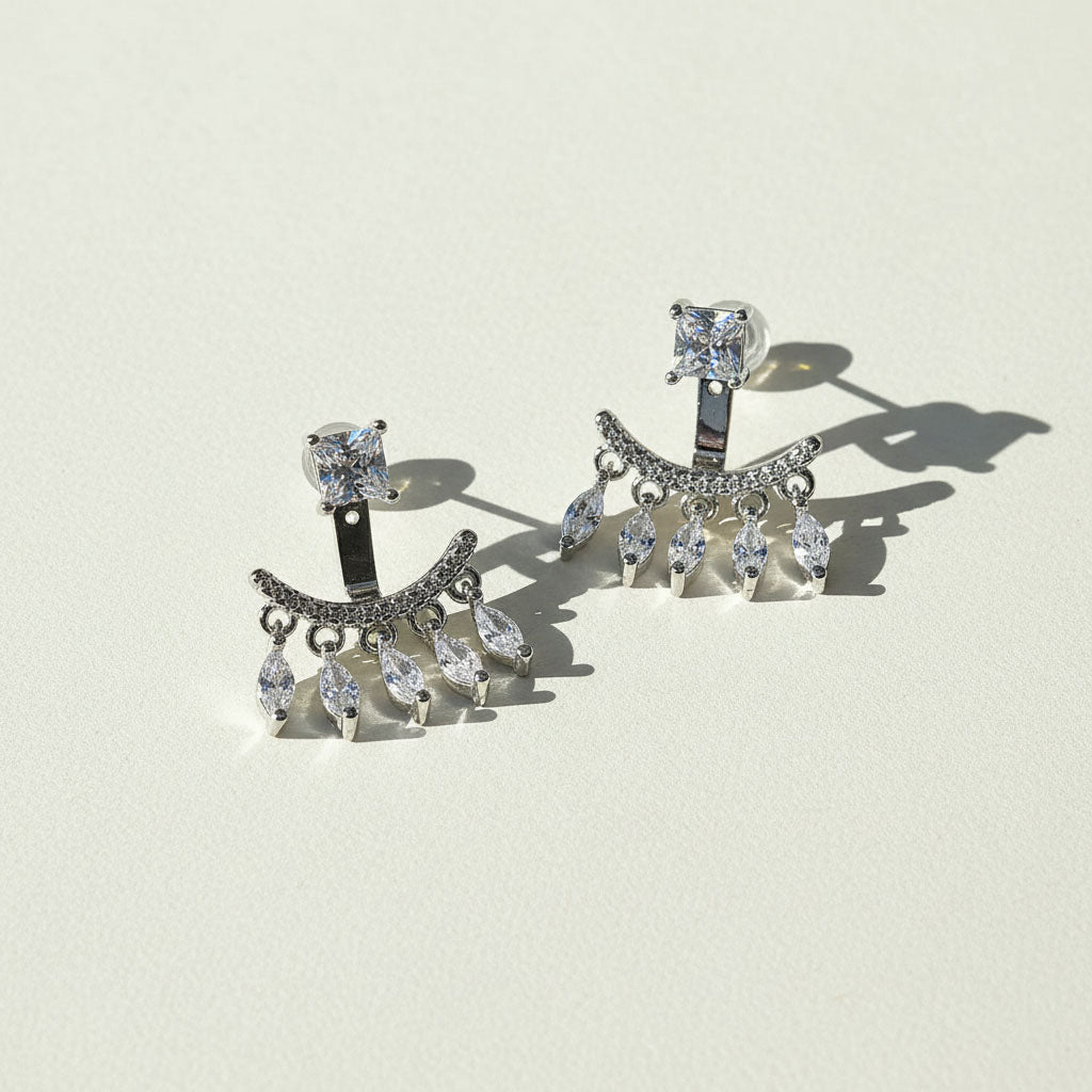 Silver earrings with clear gemstones on a light beige background
