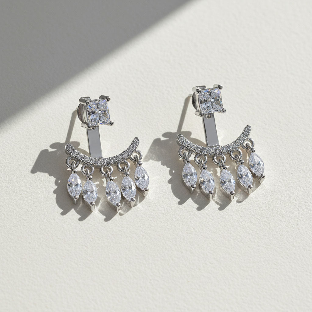 Pair of silver chandelier earrings with clear gemstones on a light background