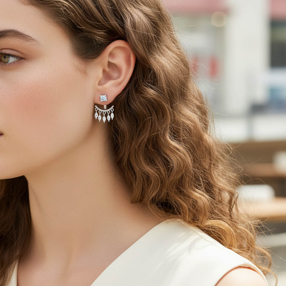 Close-up of a woman wearing a silver earring with a central gemstone and dangling elements.