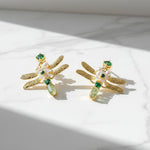 Dragonfly-shaped earrings with green and pearl details on a light background